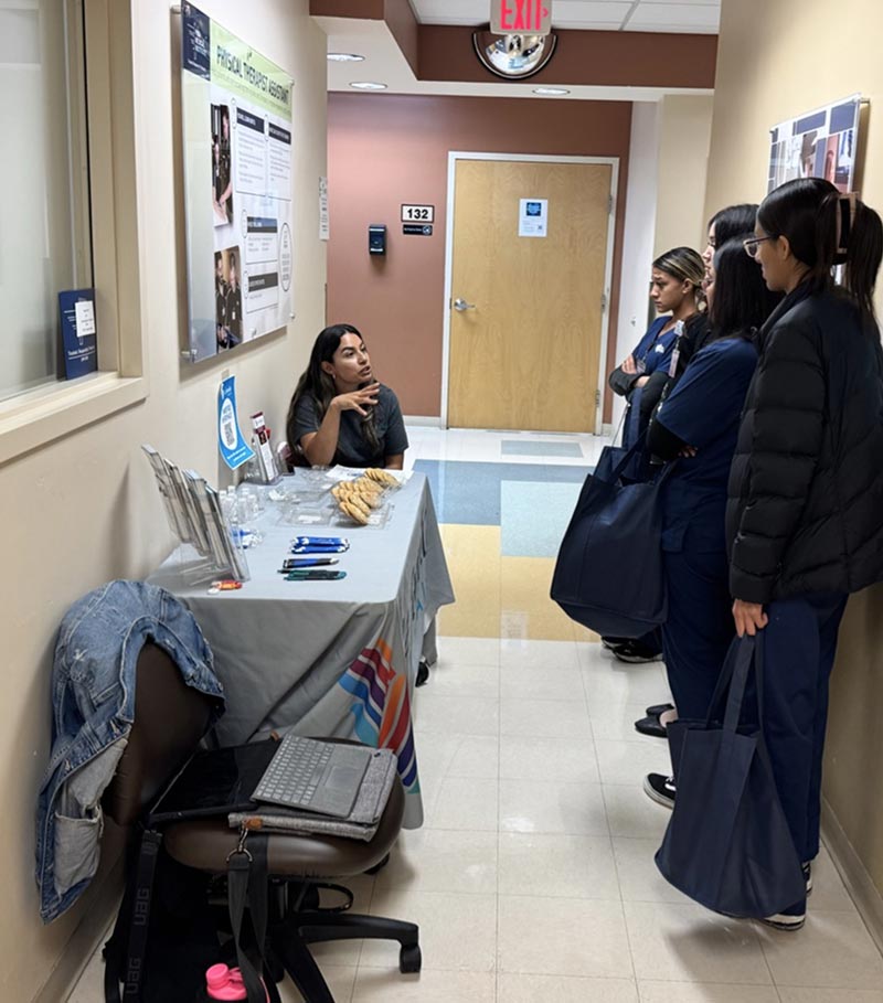 La Familia Employee behind La Familia Table speaking to volunteers